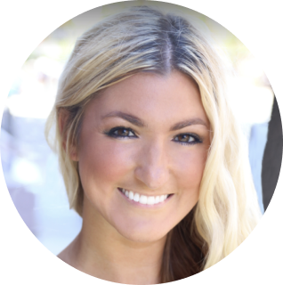 A woman with long, blonde hair and a white smile is looking at the camera. The background is slightly blurred.