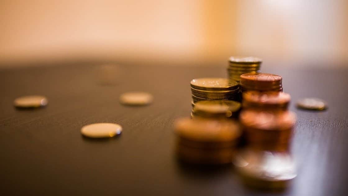 Stacks of coins in varying heights on a dark surface, with a blurred background emphasizing the focus on the nearest stack.